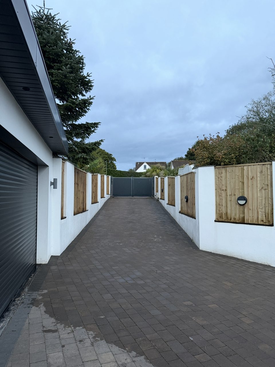 Timber fence panels set into white rendered walls along a driveway