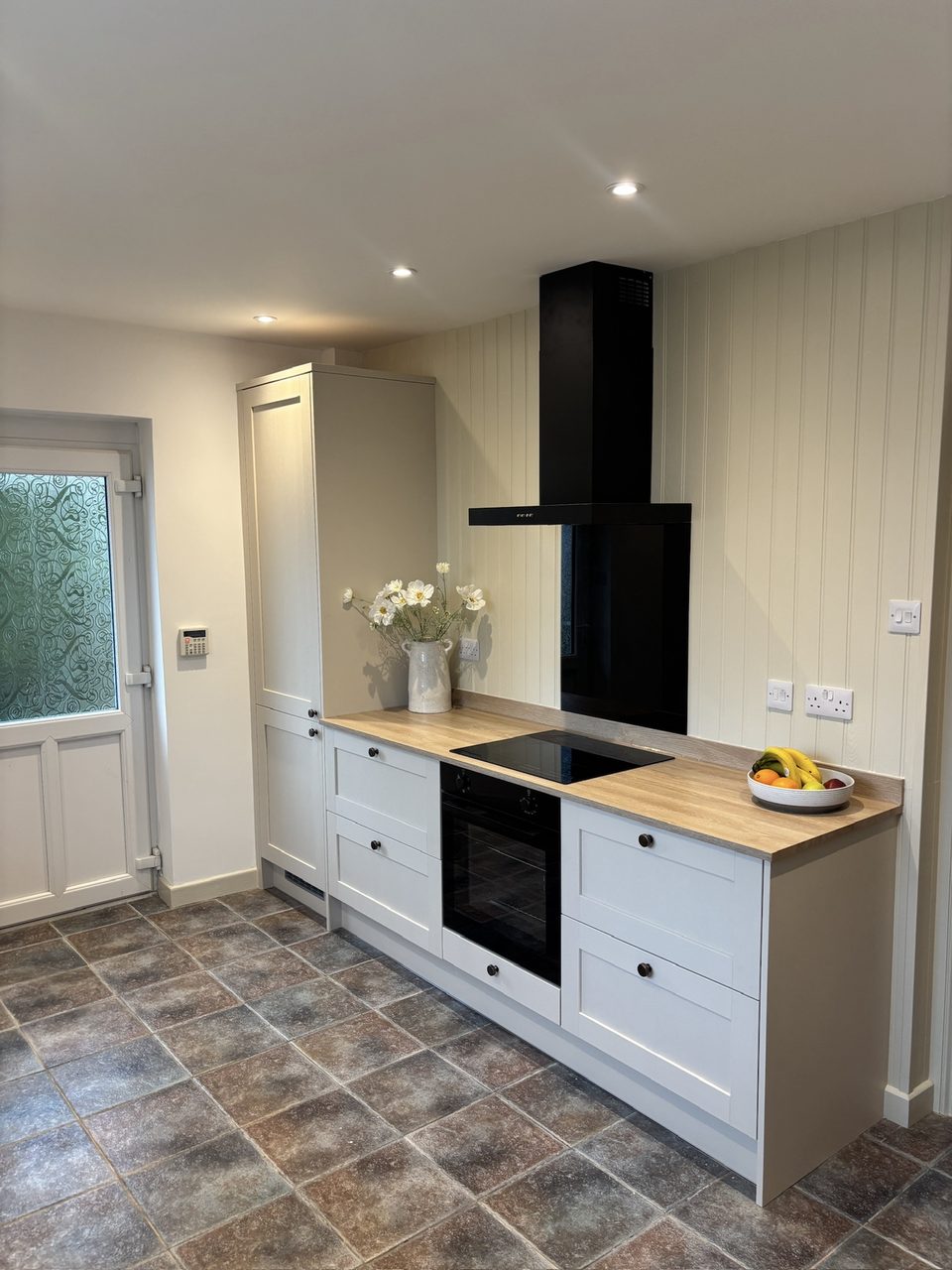Shaker kitchen run with oak-effect worktop and black chimney hood